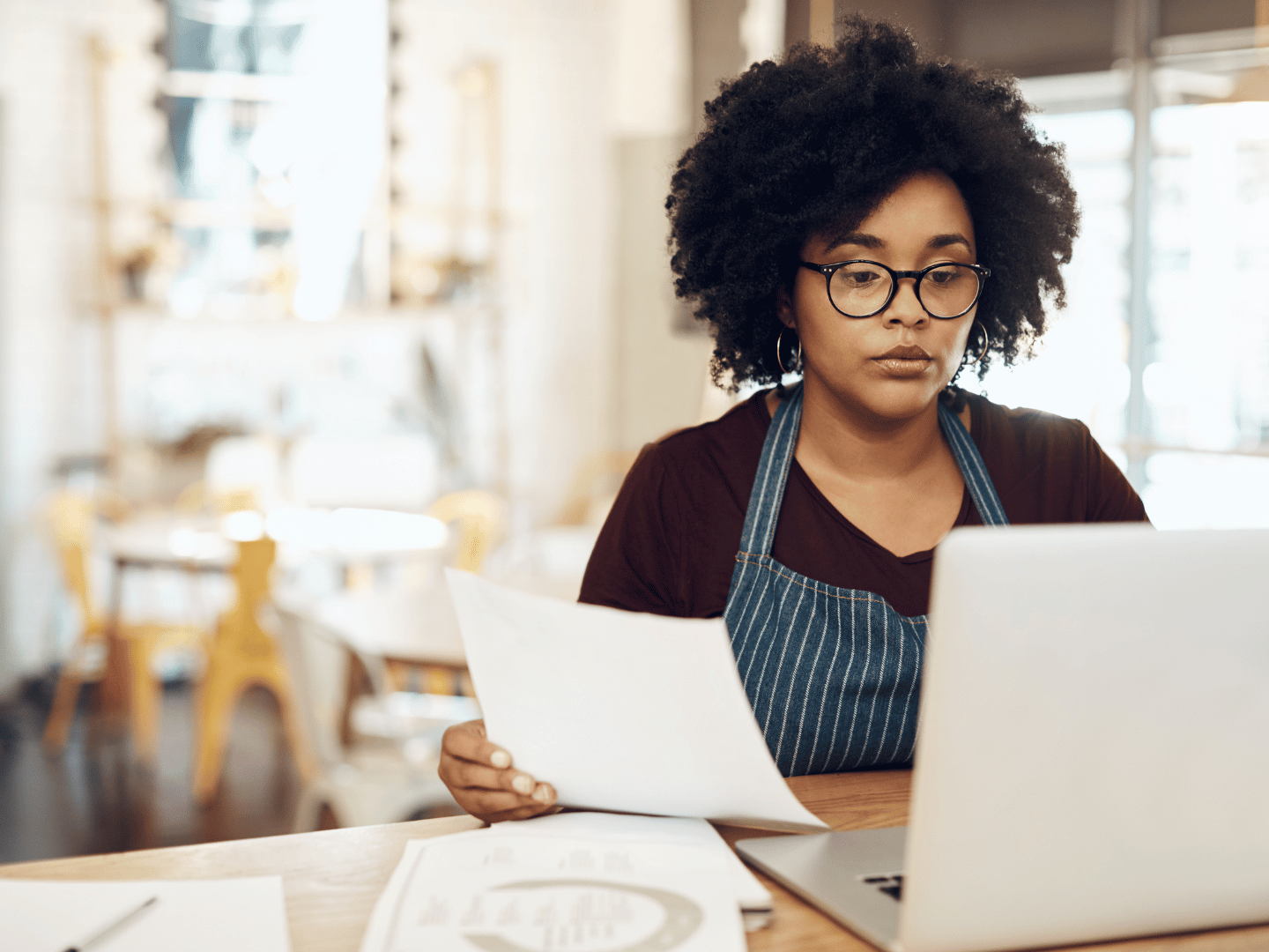 Small business owner in her store calculating her costs on her laptop